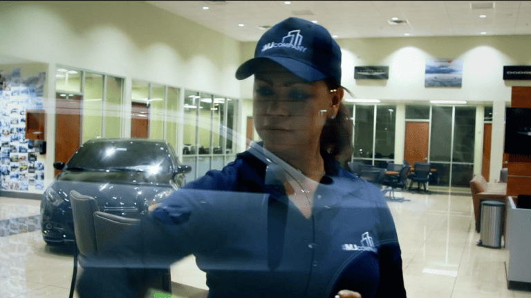 Woman wiping glass in auto showroom as part of commercial cleaning services in Phoenix, AZ